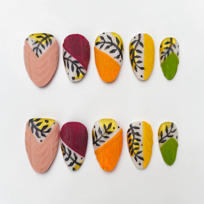 Auntie Cookies Nails: Set of 10 press-on nails with abstract leaf and swirl designs in pink, orange, yellow, green, and burgundy.