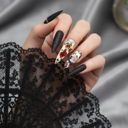 Auntie Cookies Nails matte black almond nails with floral print, red gems, pearls, and gold accents.