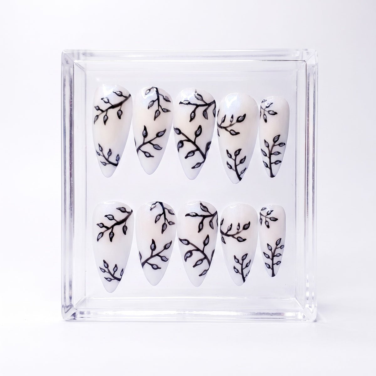 Auntie Cookies Nails almond press-on nails with pearlescent white base and metallic silver botanical branch designs.