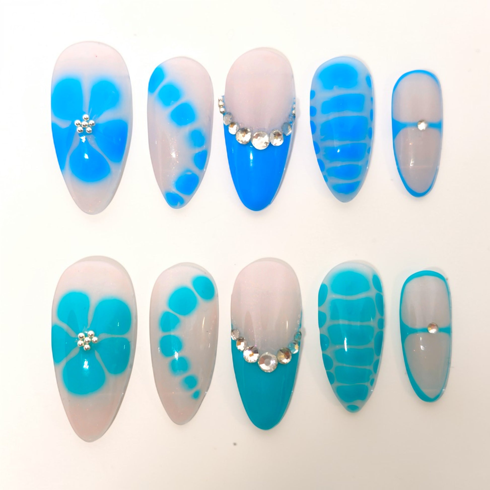 Auntie Cookies Nails Aqua Lagoon press on nails with milky bases, aqua accents, floral designs, and crystal details.
