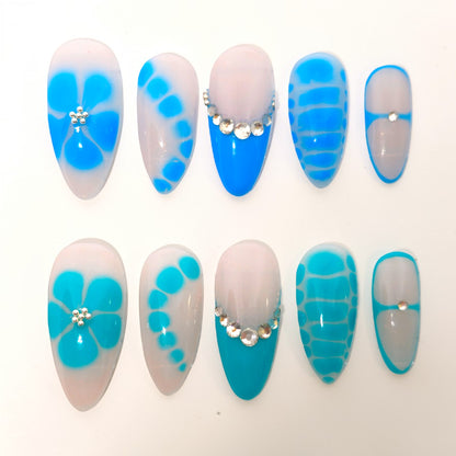 Auntie Cookies Nails Aqua Lagoon press on nails with milky bases, aqua accents, floral designs, and crystal details.