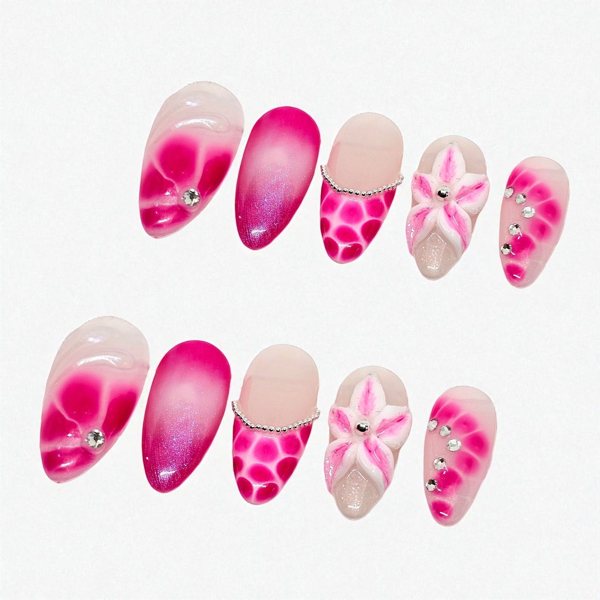 Auntie Cookies Nails: Almond-shaped press-on nails with pink and fuchsia gradient, floral 3D designs, rhinestones, and scale patterns.