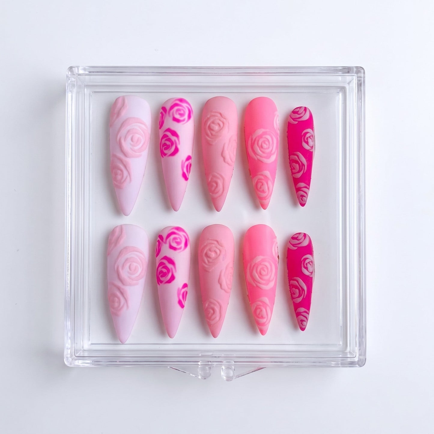 Auntie Cookies Nails almond-shaped press-on nails featuring a matte pink gradient with 3D embossed rose patterns.