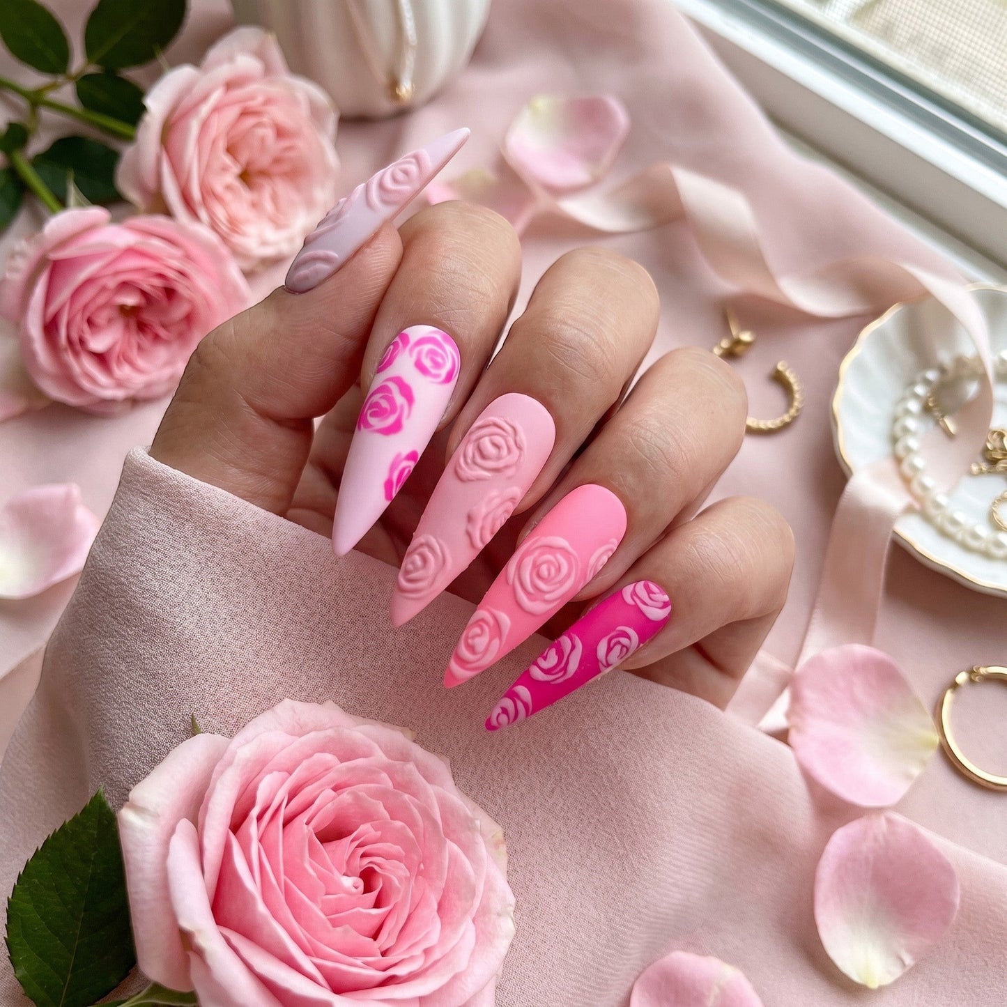 Auntie Cookies Nails almond press-on nails with matte pink gradient, 3D embossed rose patterns, and floral accents.