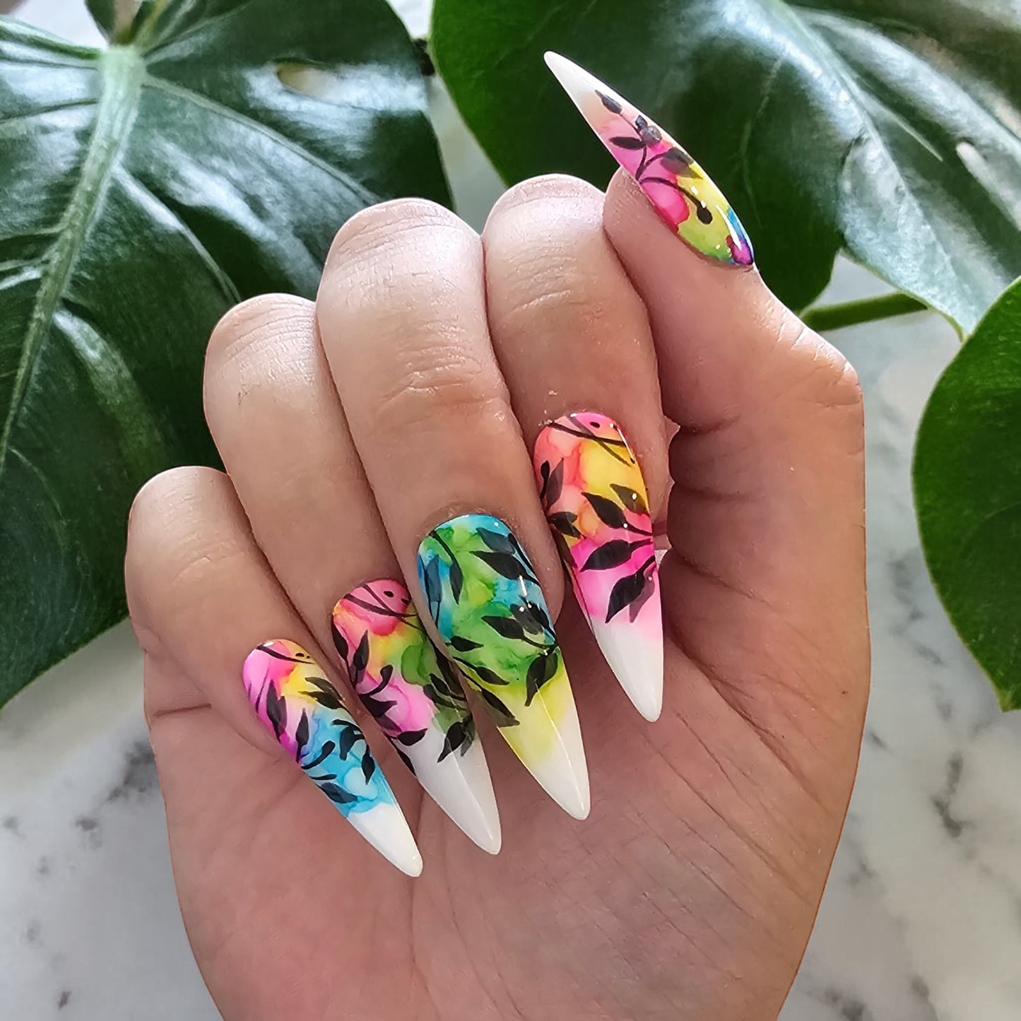 Auntie Cookies Nails: Almond-shaped press-on nails with vibrant watercolor floral design and black foliage accents.