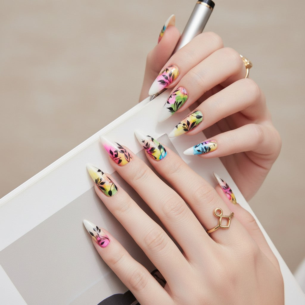 Auntie Cookies Nails: Almond-shaped press-on nails with a watercolor-inspired design of black foliage on a white base with vibrant pink, yellow, green, and blue accents.