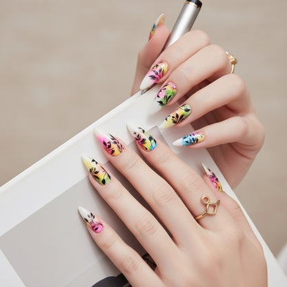 Auntie Cookies Nails: Almond-shaped press-on nails with a watercolor-inspired design of black foliage on a white base with vibrant pink, yellow, green, and blue accents.