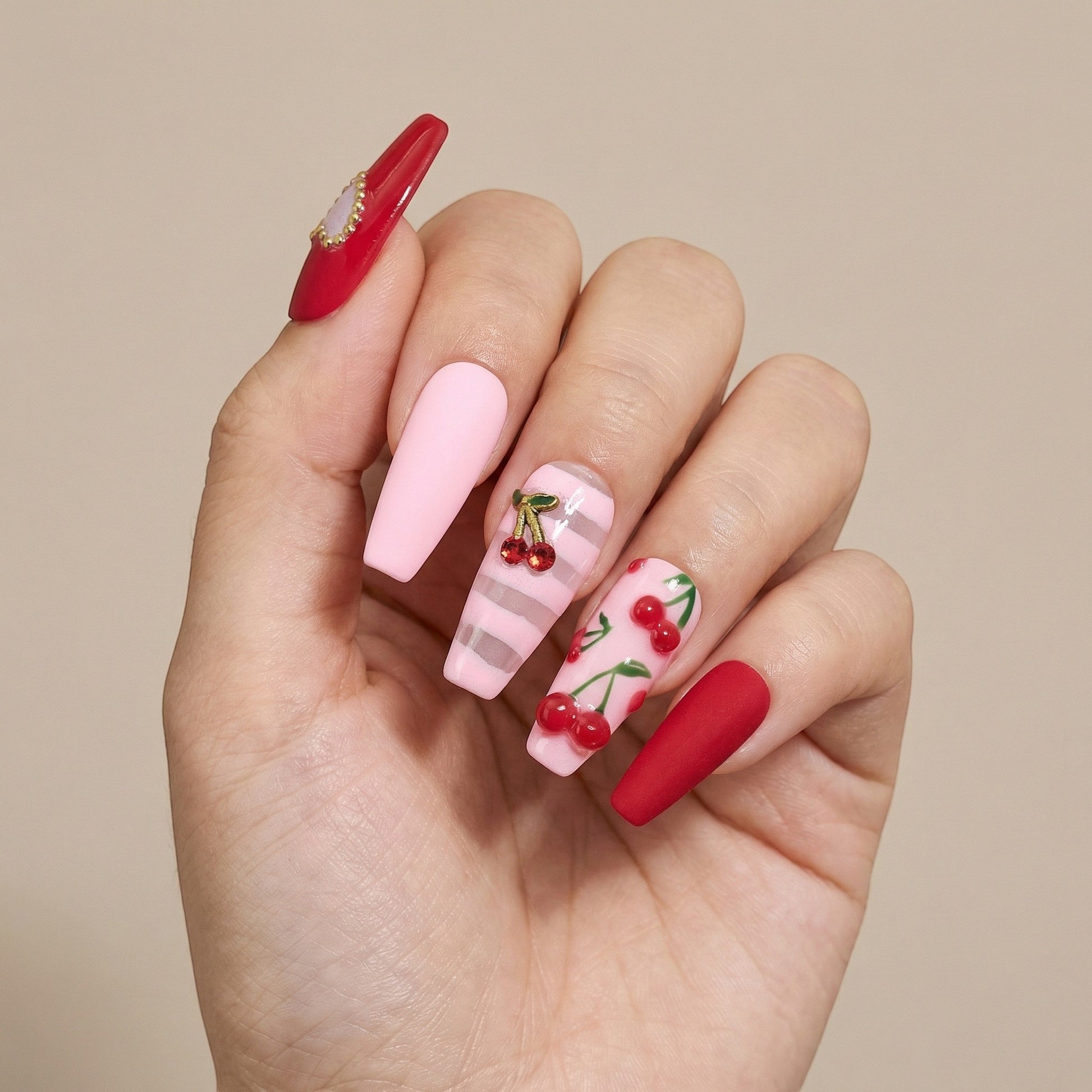 Auntie Cookies Nails: Coffin press on nails with cherry, heart gem, and stripe designs in red, pink, and sheer pink.