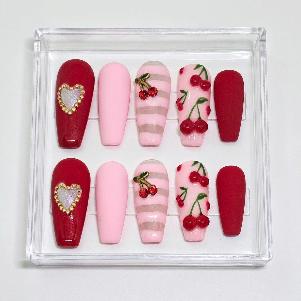 Auntie Cookies Nails coffin press on nails with red heart gem, pink, pink stripes, and cherry designs.