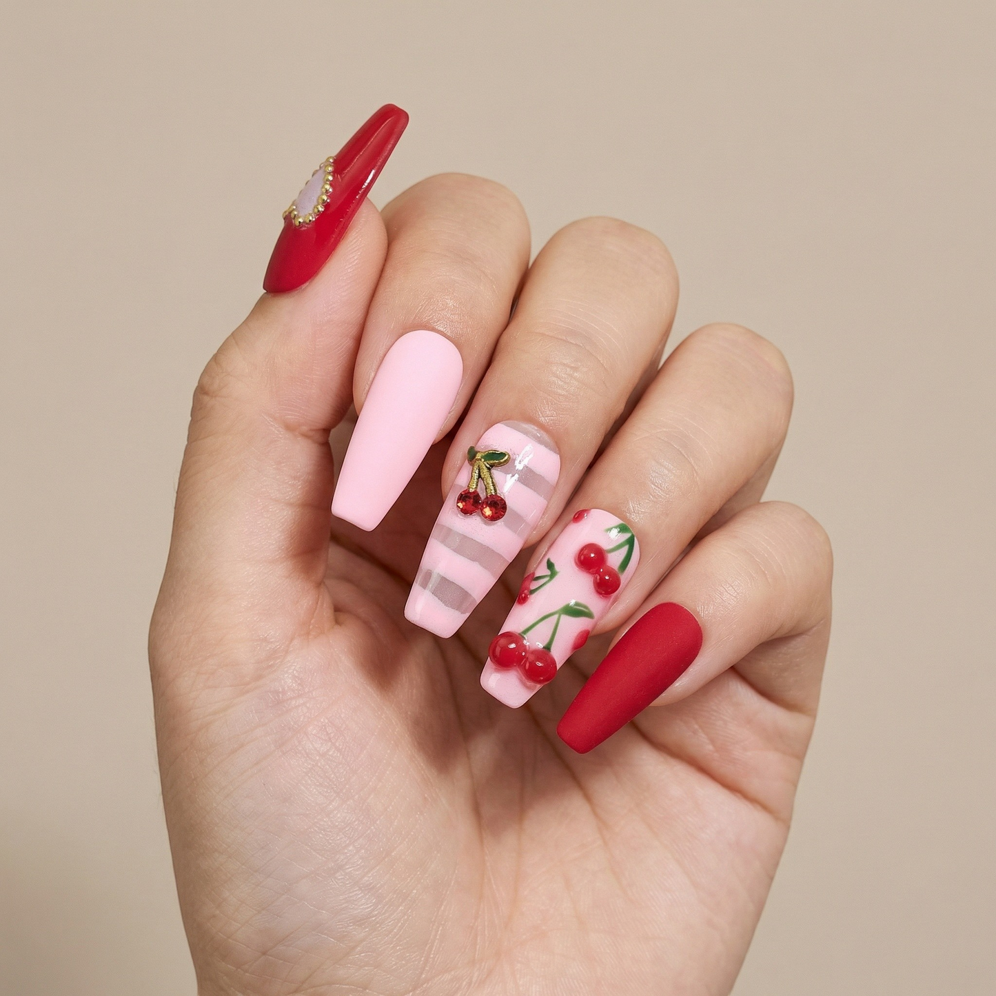 Auntie Cookies Nails: Coffin press-on nails in matte red, pastel pink, and sheer pink with stripes, featuring hand-painted cherry designs and 3D cherry charms.