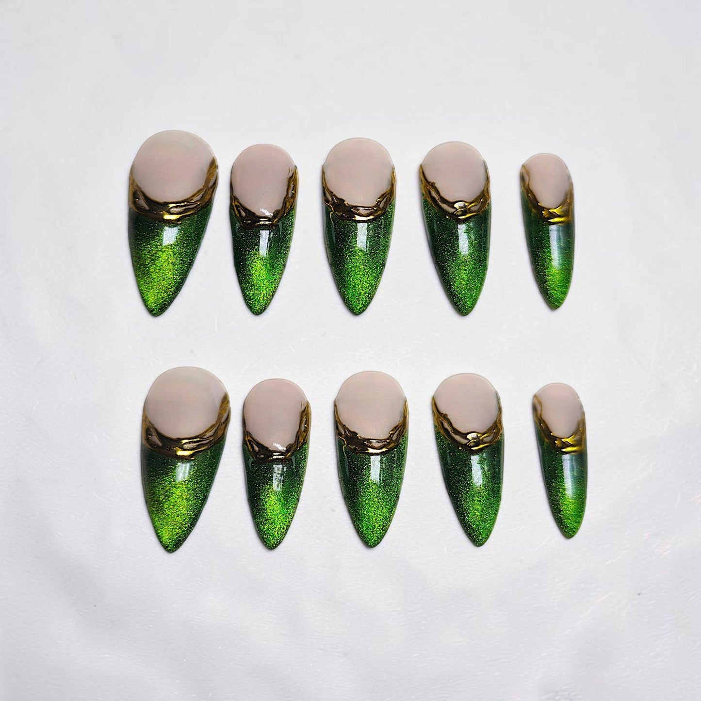 Auntie Cookies Nails almond press-on nails with emerald green cat-eye finish, nude base, and gold metallic accents.