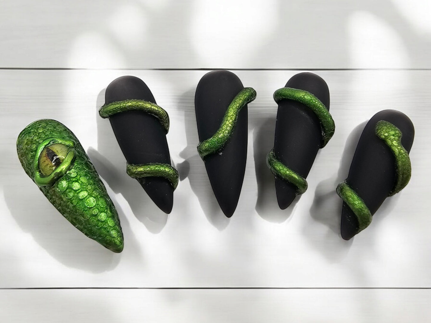 Auntie Cookies Nails: Black stiletto press-on nails with green chrome snake wraps and one dragon eye nail.