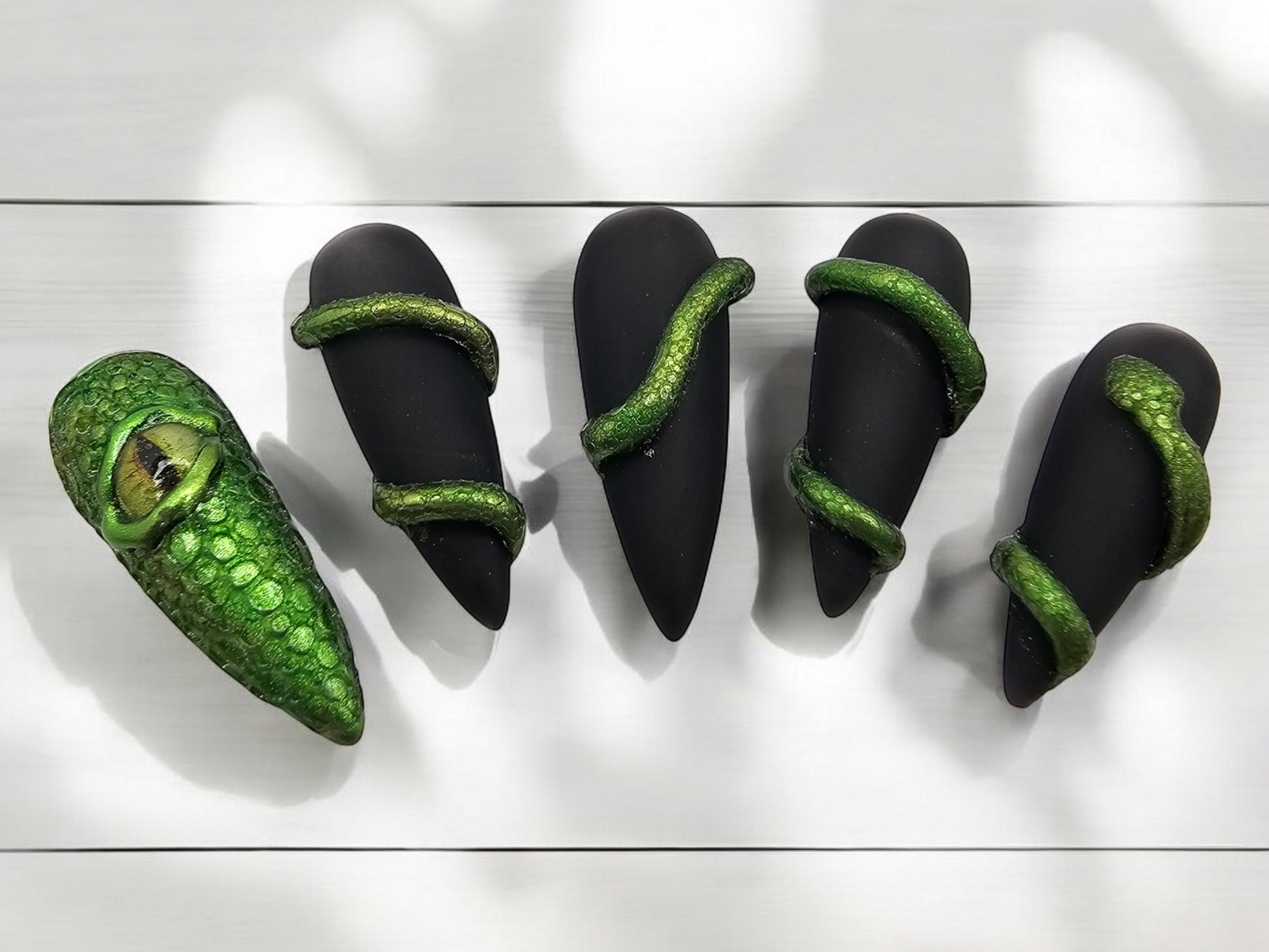 Auntie Cookies Nails: Black stiletto press-on nails with green chrome snake wraps and one dragon eye nail.