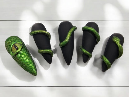 Auntie Cookies Nails: Black stiletto press-on nails with green chrome snake wraps and one dragon eye nail.