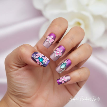 Auntie Cookies Nails press on nails with purple and rose gold gradient, 3D pink flowers, turquoise gems, silver leaves, and rhinestones.