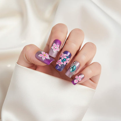 Auntie Cookies Nails Enchanted Azure Garden press-on nails with purple, rose gold gradient, 3D flowers, rhinestones, and silver leaf details.