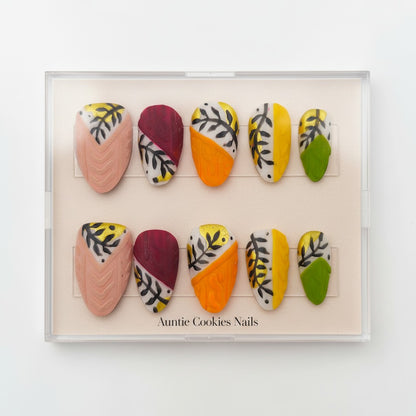 Auntie Cookies Nails: Set of 10 press-on nails in various designs including cable knit texture, leaf patterns, and color blocking in pink, burgundy, orange, yellow, and green.