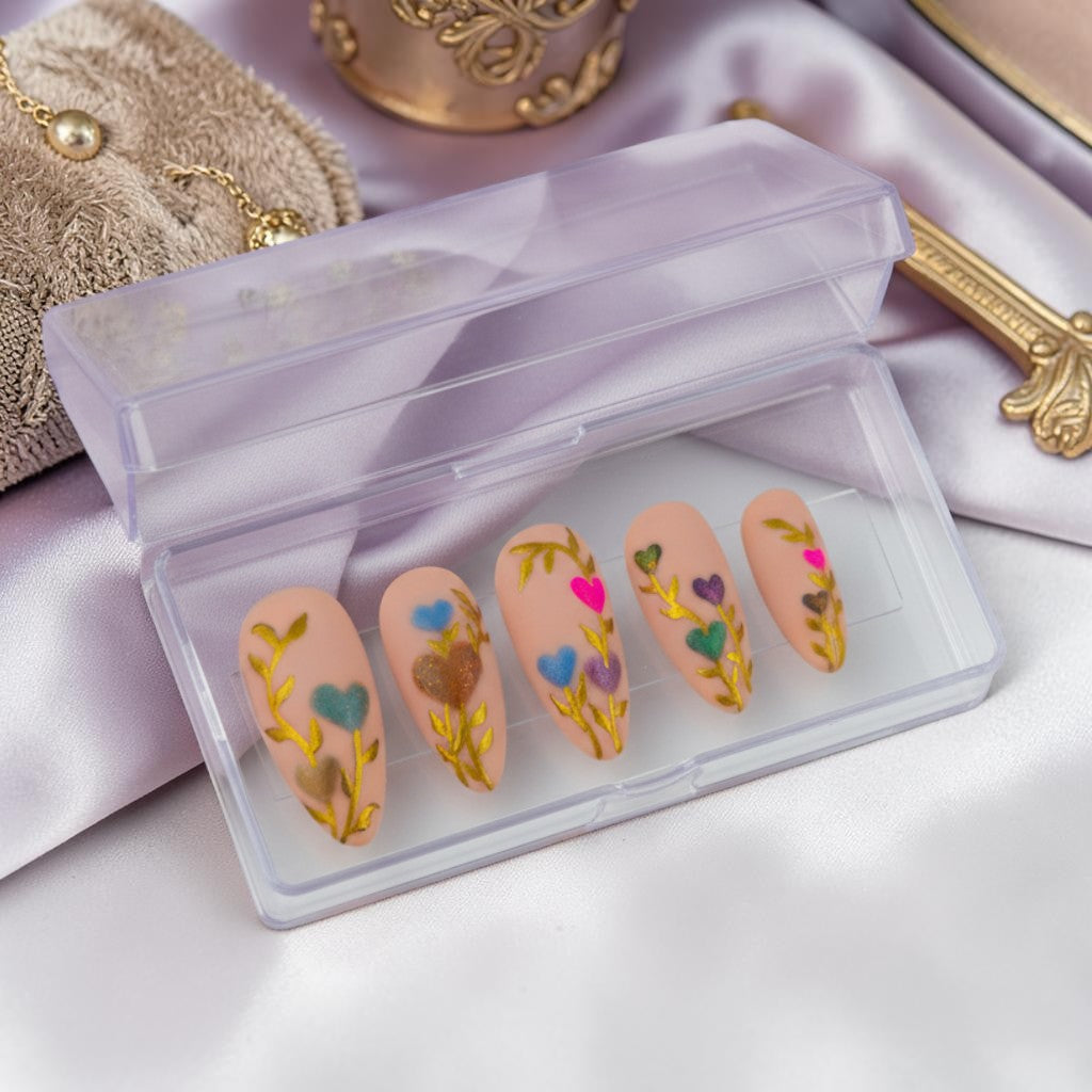 Auntie Cookies Nails: Set of 10 nude press-on nails with gold vine design and heart-shaped tips in pink, blue, purple, and green.