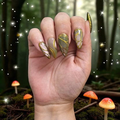 Auntie Cookies Nails Forest Fairy press on nails with green and gold wing patterns in a magical woodland setting.
