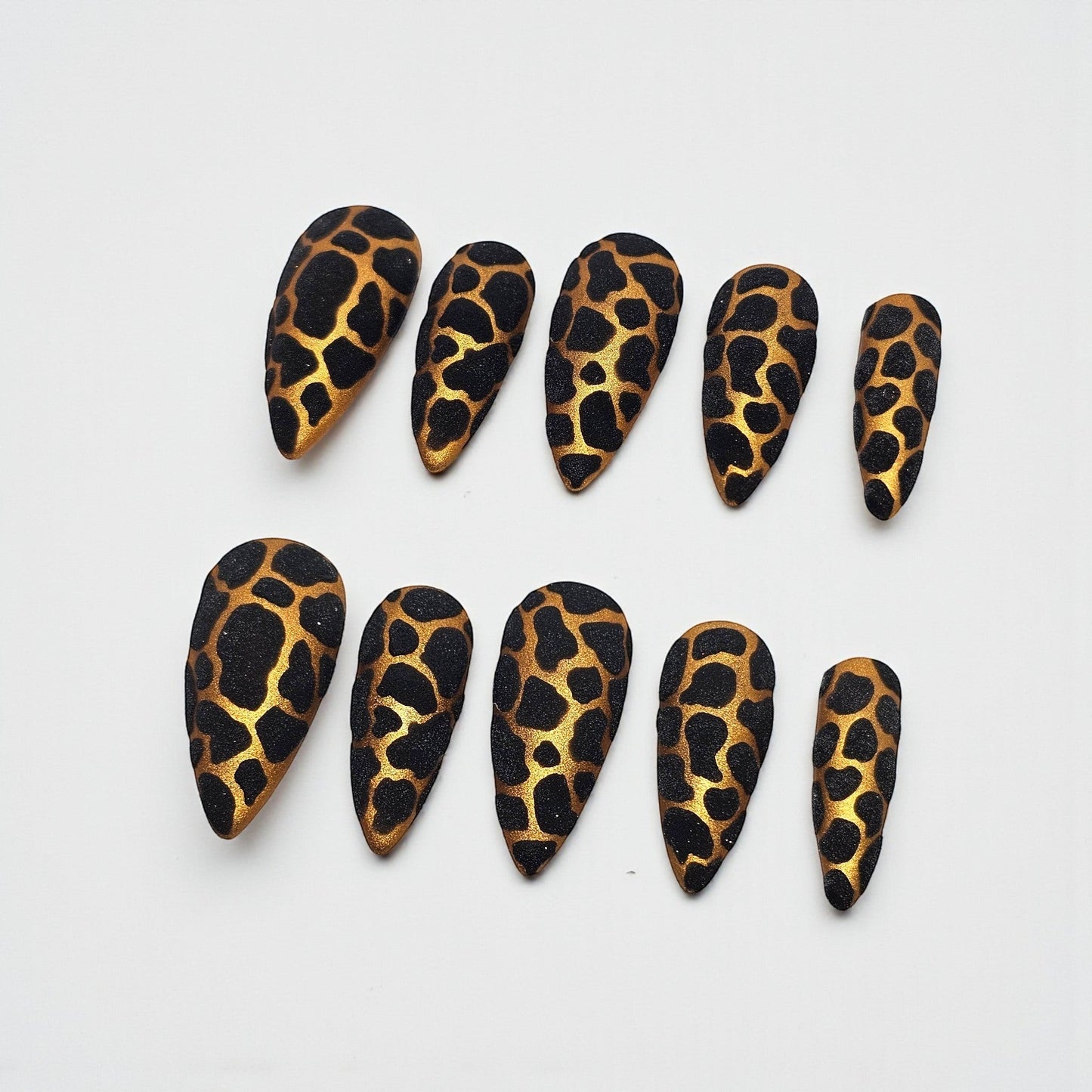 Auntie Cookies Nails stiletto press on nails with black and gold giraffe print and glitter finish.