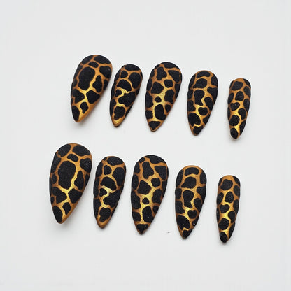 Auntie Cookies Nails stiletto press on nails with black and gold giraffe print and glitter finish.