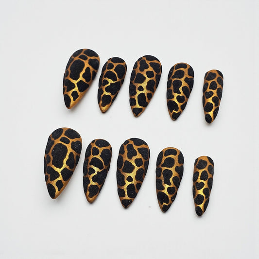 Auntie Cookies Nails stiletto press on nails with black and gold giraffe print and glitter finish.