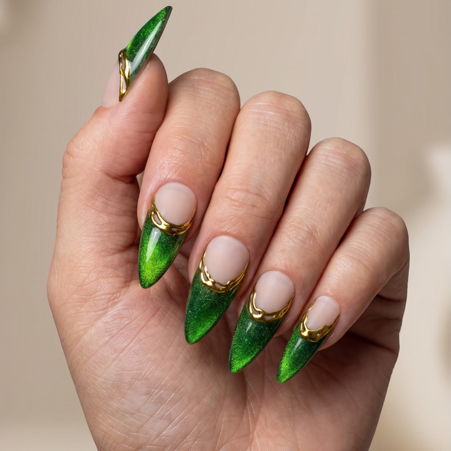 Auntie Cookies Nails almond press-on nails with emerald green cat-eye finish, nude base, and gold metallic French tips.