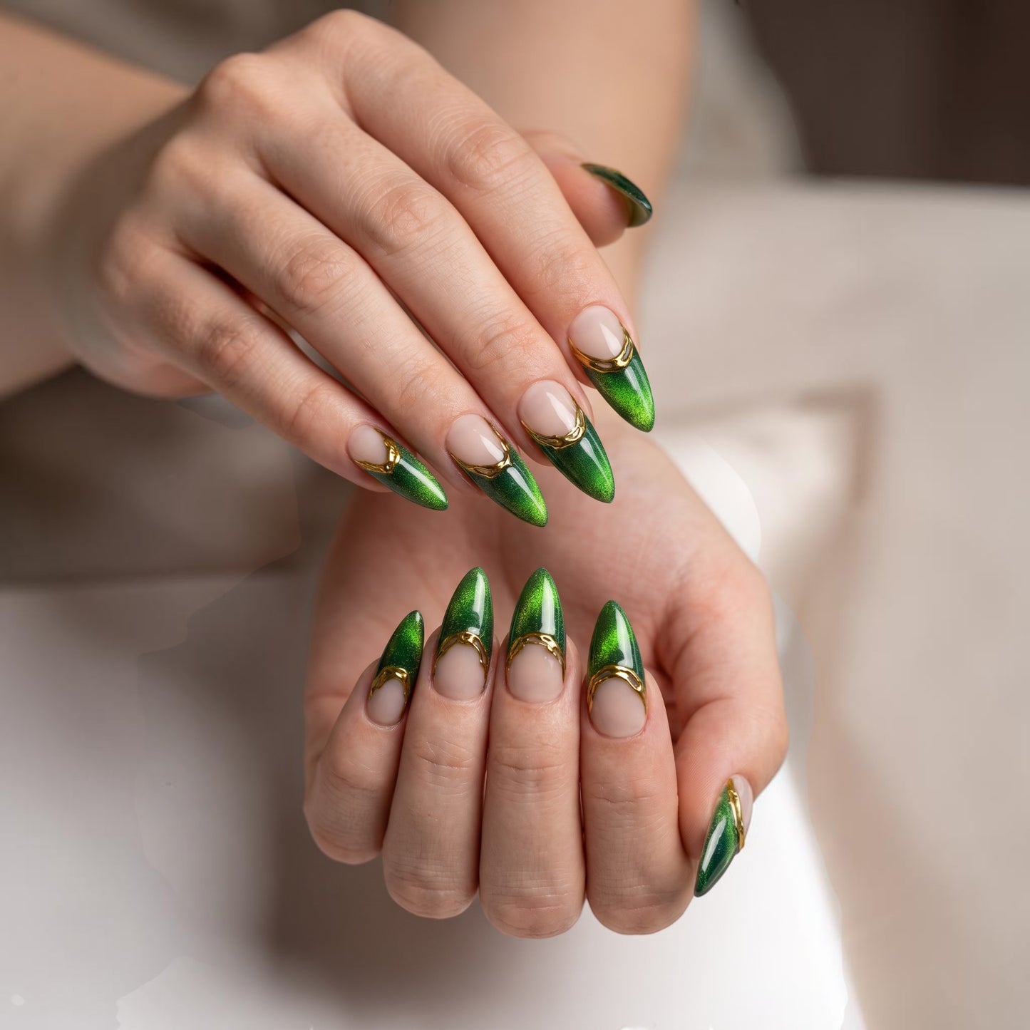 Auntie Cookies Nails almond press-on nails with emerald green cat-eye finish, nude base, and gold metallic French tips.