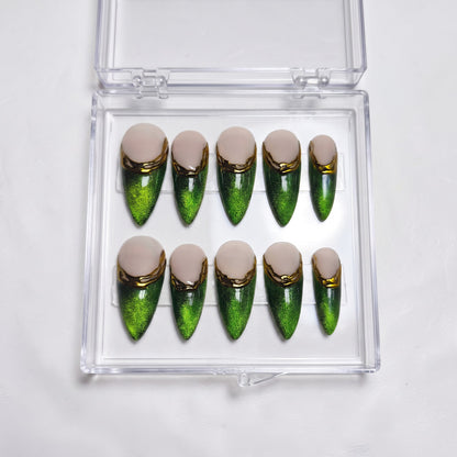 Auntie Cookies Nails almond press-on nails with emerald green cat-eye finish, nude base, and gold metallic French tips.
