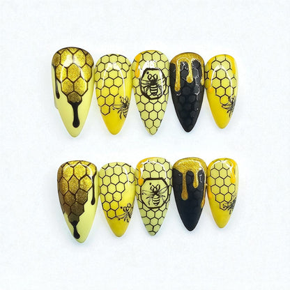 Auntie Cookies Nails: Almond-shaped press-on nails with yellow, black, and gold honeycomb, bee, and dripping honey designs.