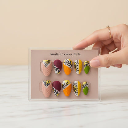 Auntie Cookies Nails: Set of 10 press-on nails in pink, burgundy, orange, yellow, and green with leaf and cable knit designs.