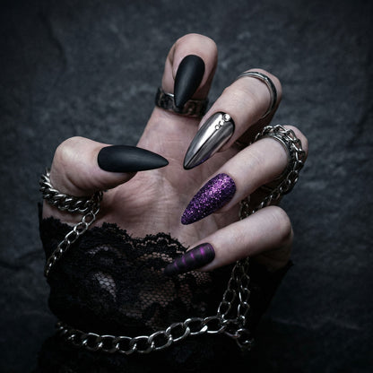 Auntie Cookies Nails: Almond-shaped press-on nails in matte black, chrome, purple glitter, and dark purple stripes with rhinestones.