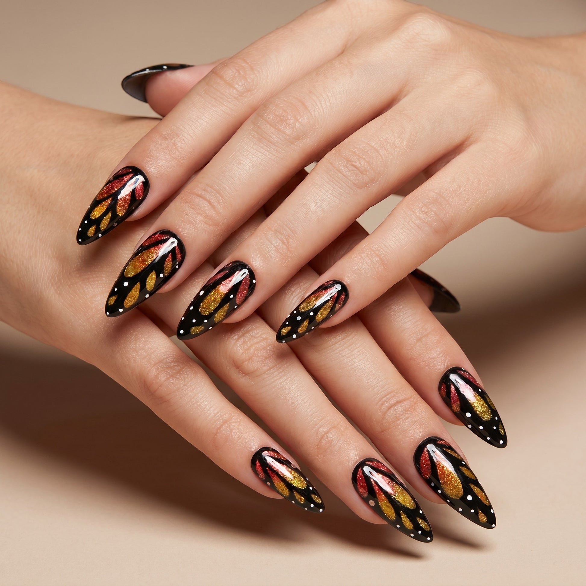 Auntie Cookies Nails almond press-on nails with black butterfly wing art, orange and gold glitter, and white dots.