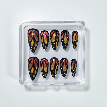 Auntie Cookies Nails Monarch butterfly press-on nails with orange and gold cat eye glitter and black wing detailing.