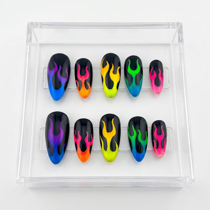 Auntie Cookies Nails almond press-on nails with a black base and vibrant neon gradient flame designs in a display box.