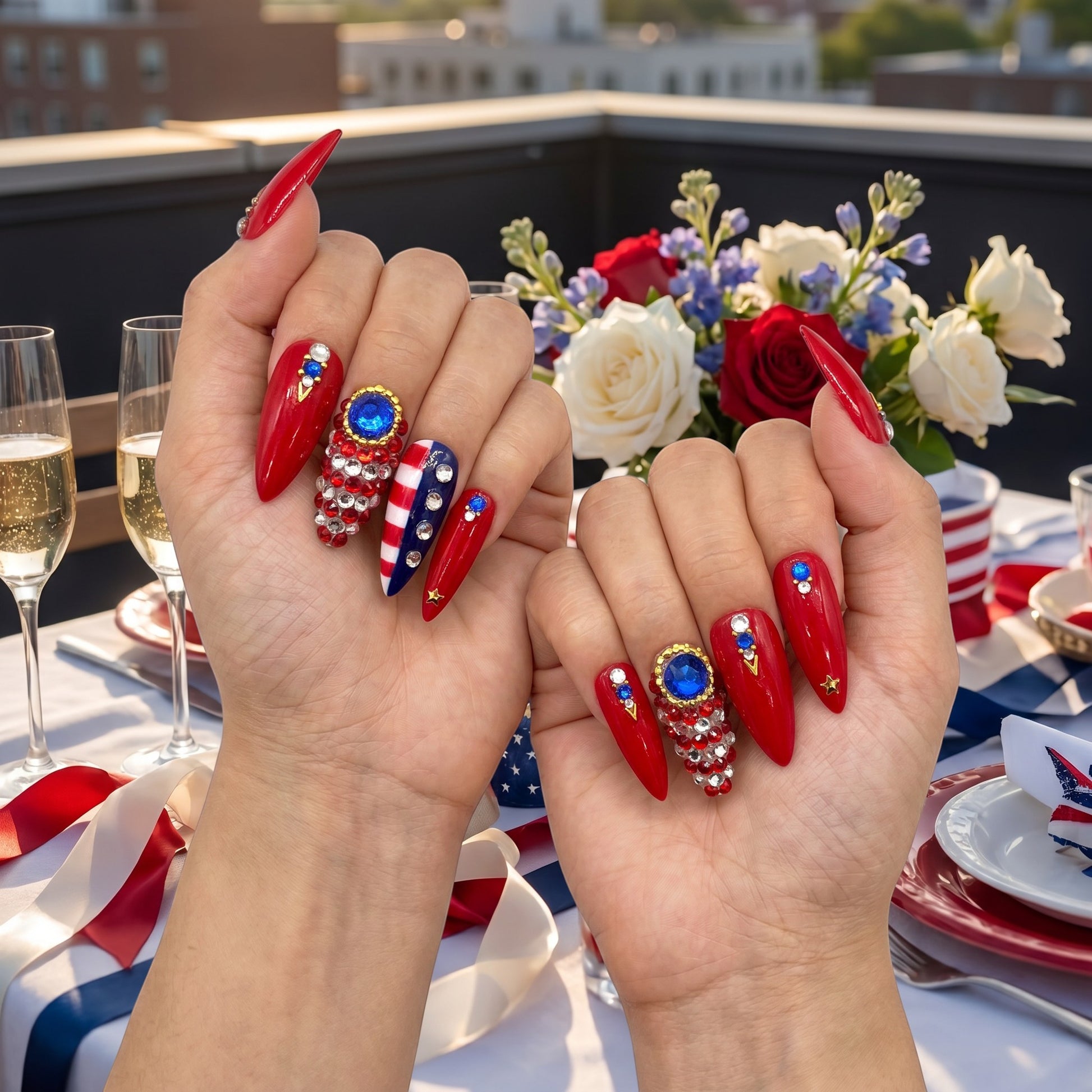 Auntie Cookies Nails stiletto press-on nails in red, white, and blue with rhinestone crystals and gold star accents.