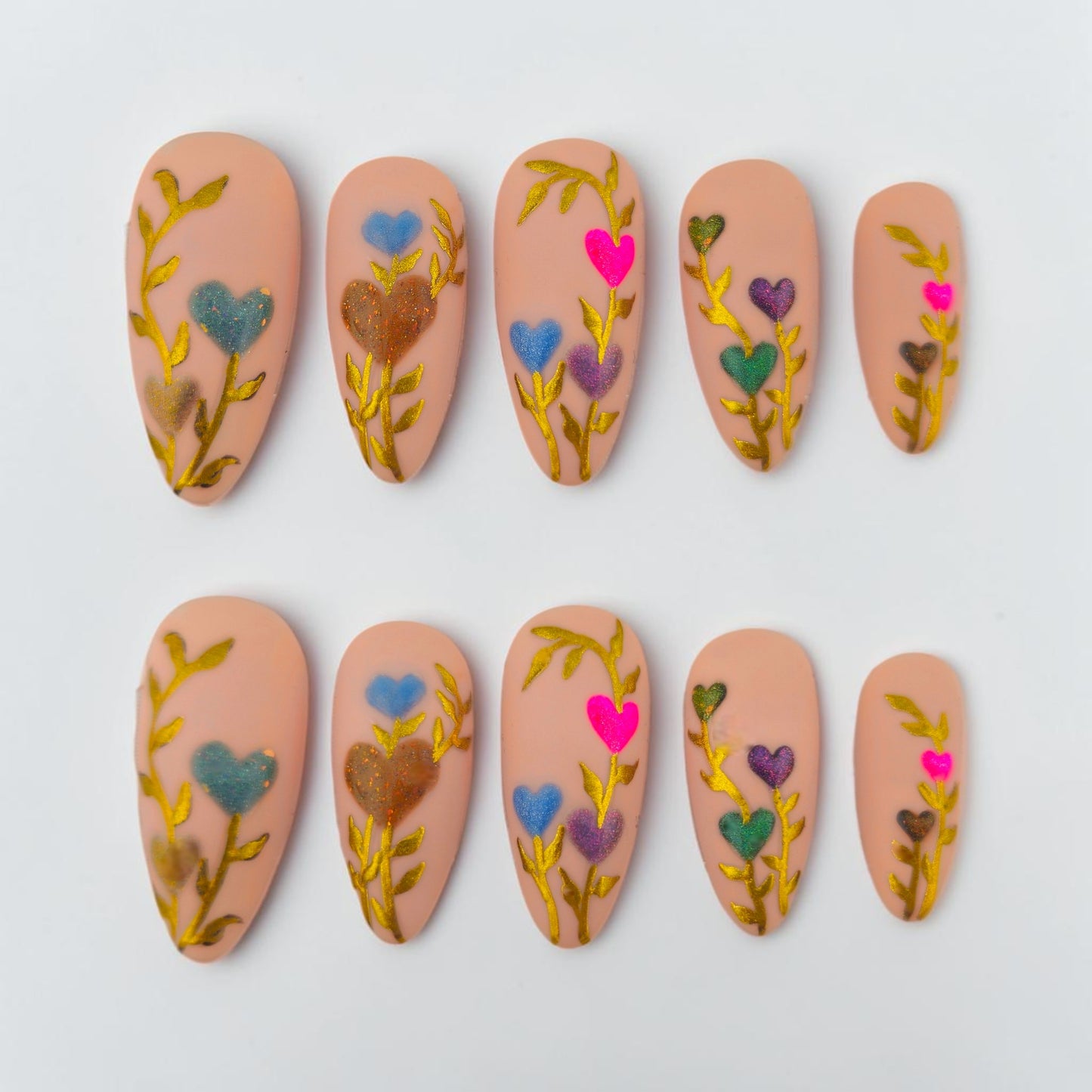 Auntie Cookies Nails: Set of 5 press-on nails in a light peach hue with gold vine accents and colorful heart-shaped flowers.