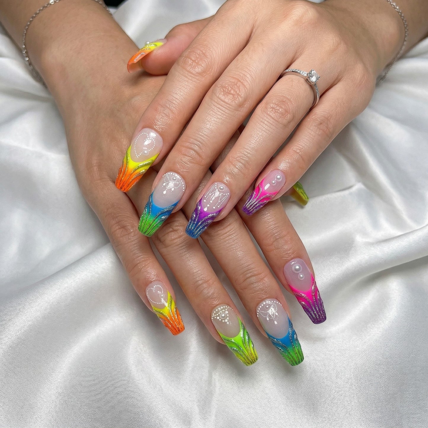 Auntie Cookies Nails: Long, coffin-shaped press-on nails with a rainbow gradient, glitter, pearls, and white bead detailing.