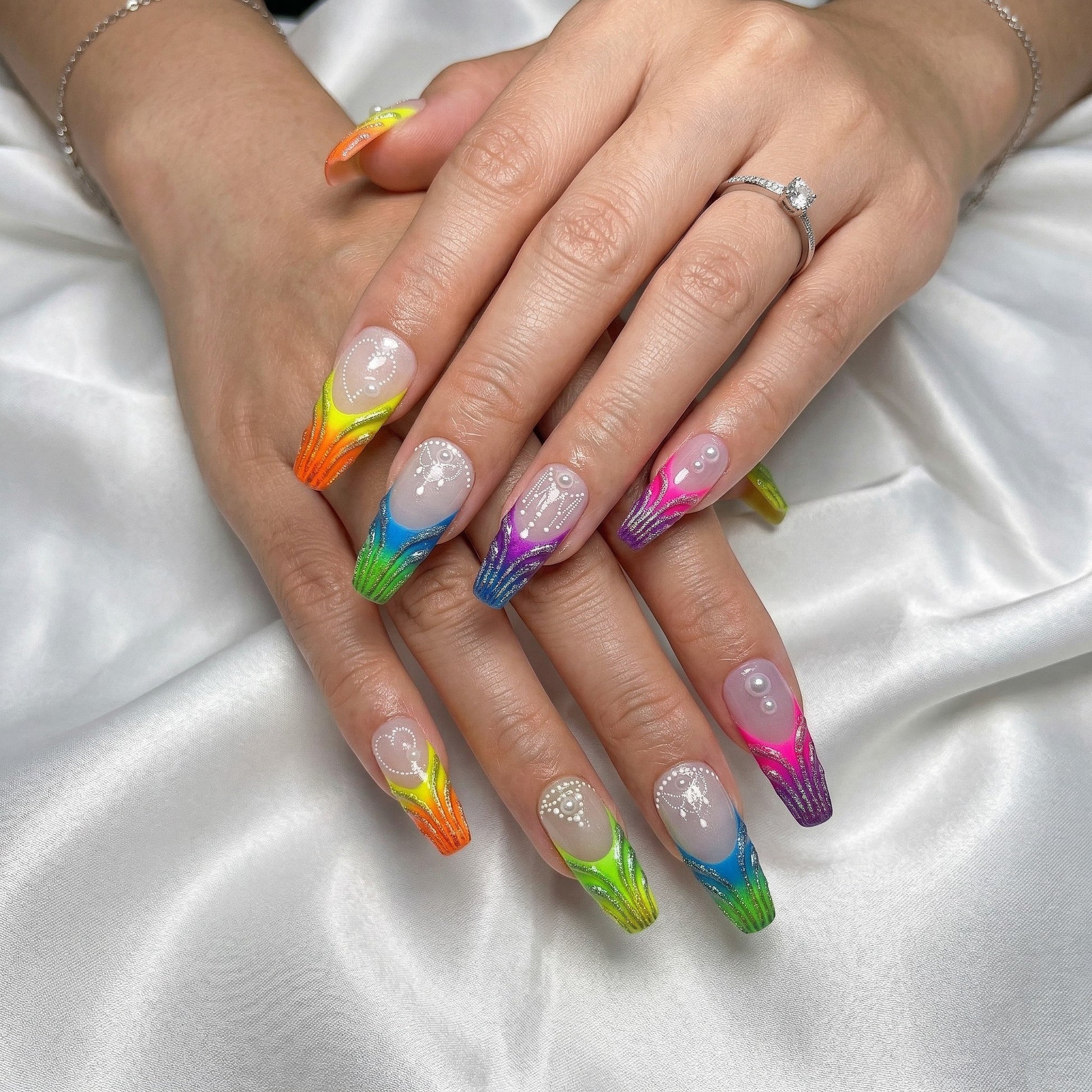 Auntie Cookies Nails: Long, coffin-shaped press-on nails with a rainbow gradient, glitter, pearls, and white bead detailing.