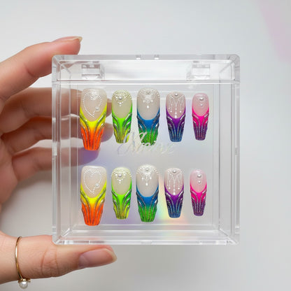 Auntie Cookies Nails: Vibrant gradient press-on nails with glitter, white bead, and pearl accents. Colors include orange, green, blue, purple, and pink.