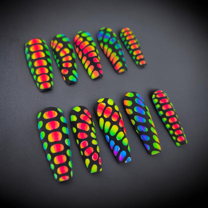 Auntie Cookies Nails coffin-shaped press-on nails with a black matte finish and a vibrant rainbow scale pattern.