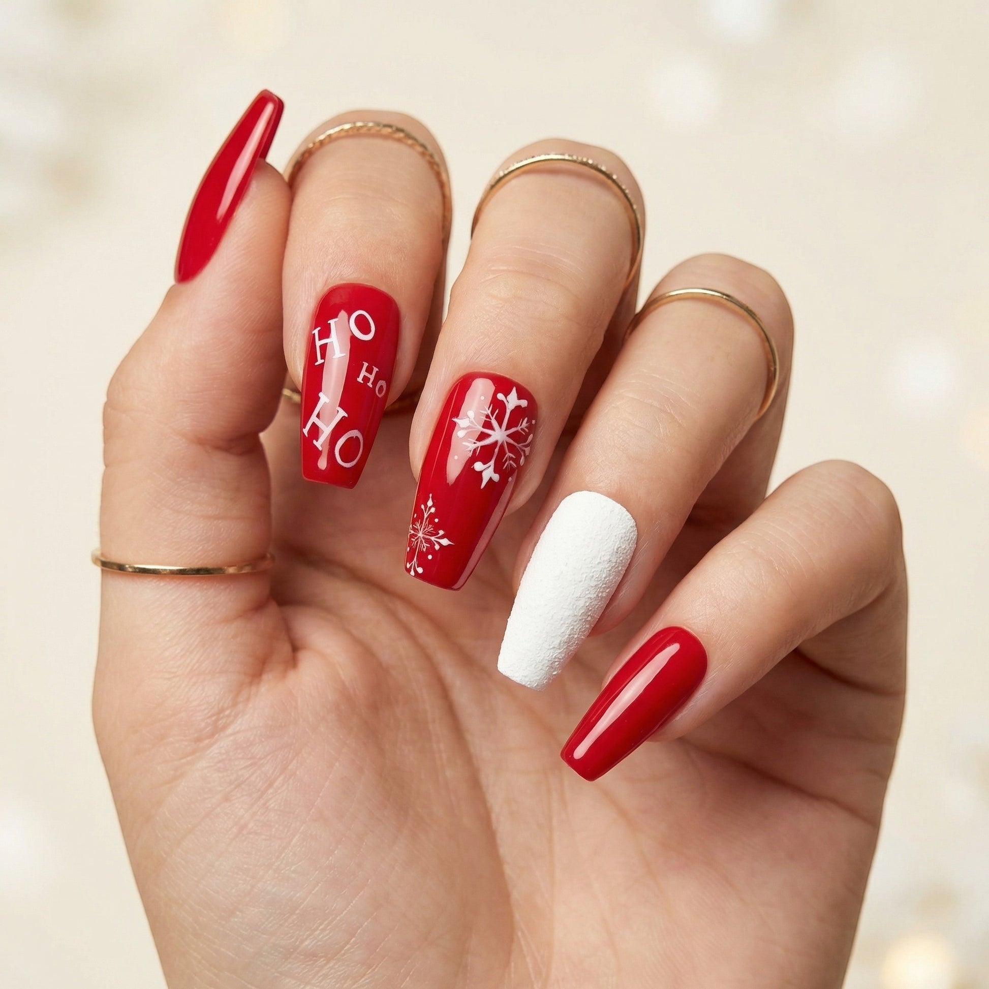 Auntie Cookies Nails festive red press-on nails with white "HO HO HO" text and snowflake designs, plus a textured white accent nail.