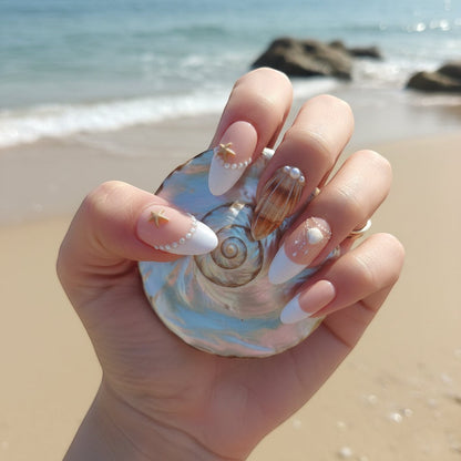 Auntie Cookies Nails: French tip press-on nails with pearl, seashell, and starfish accents on a beach background.
