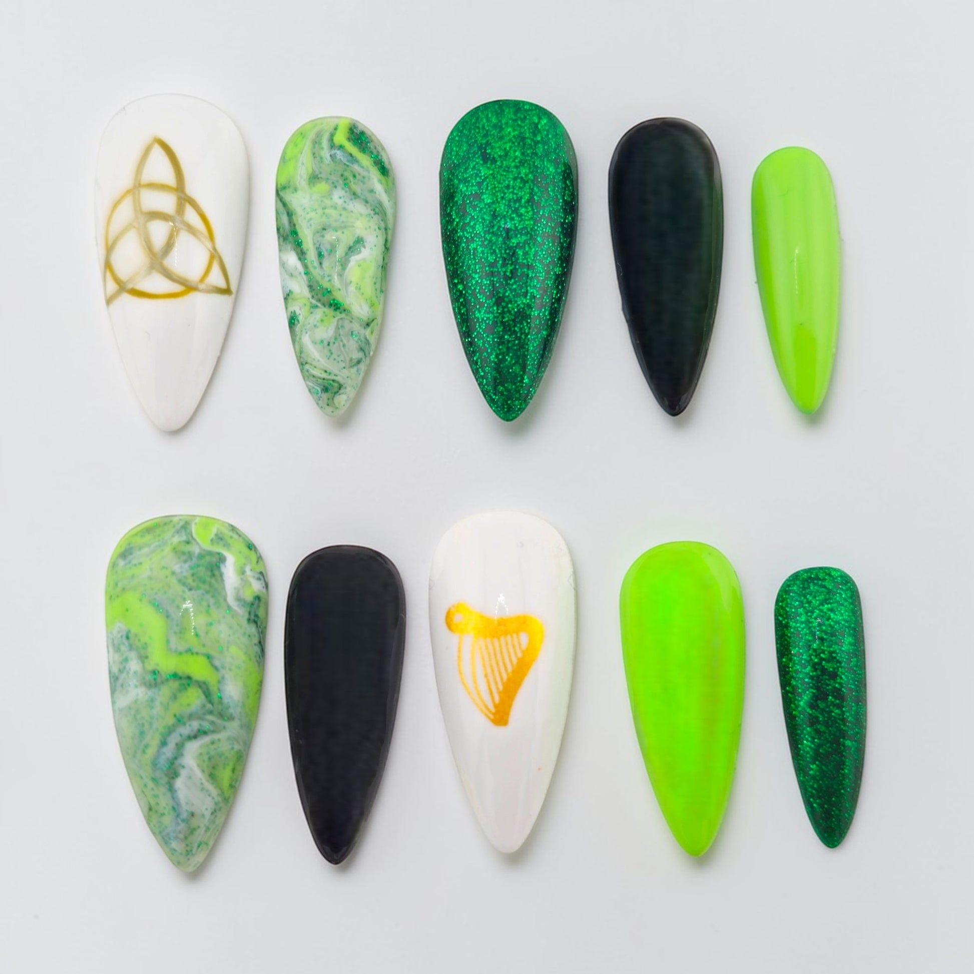 Auntie Cookies Nails: Set of 10 press-on nails in green marble, glitter, black, and white with gold Celtic knot and harp designs.