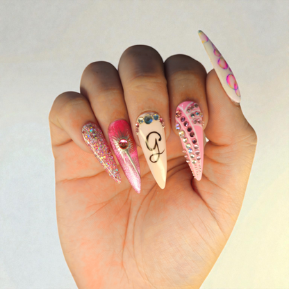 Auntie Cookies Nails: Set of 5 stiletto press-on nails in pink, white, and glitter with rhinestones and a black 'G' initial.