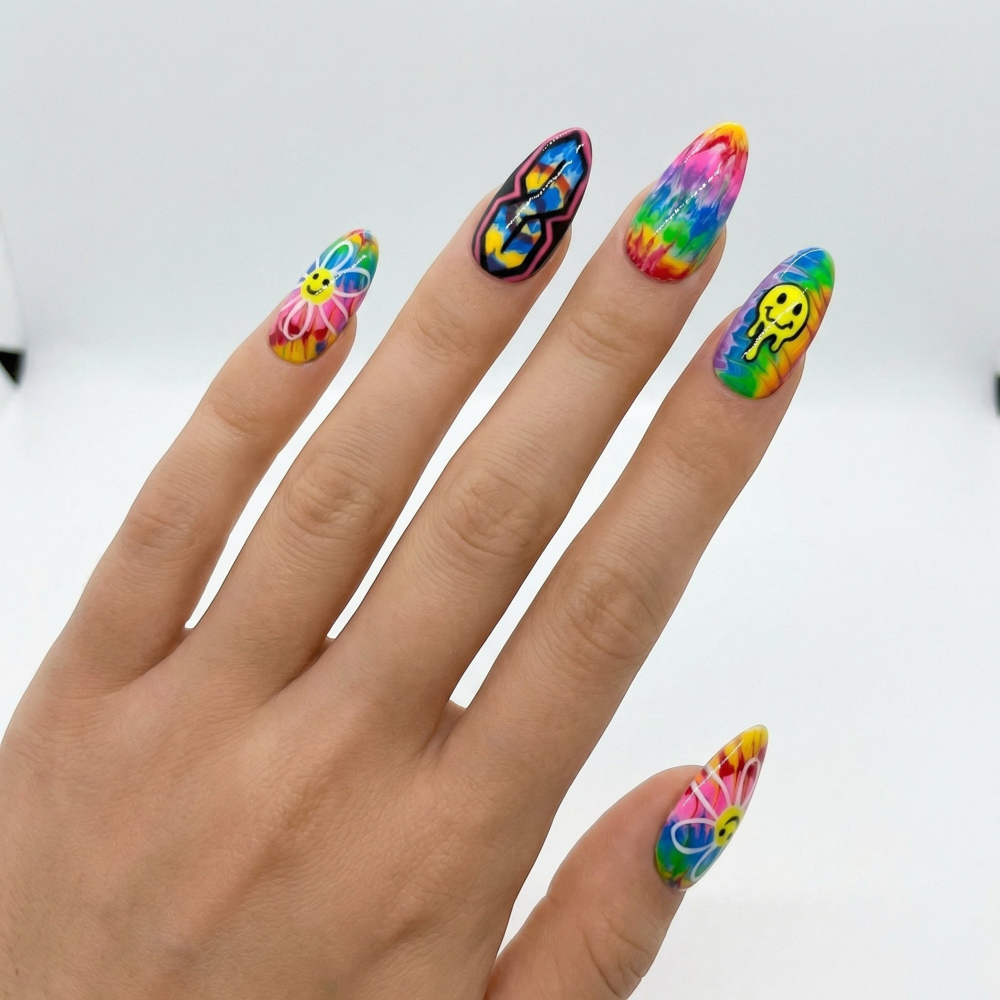 Auntie Cookies Nails: Rainbow tie-dye press-on nails with smiley faces, peace signs, and psychedelic designs.