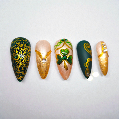 Auntie Cookies Nails: Emerald green and champagne press-on nails with gold Celtic designs, clover motifs, and rhinestones.