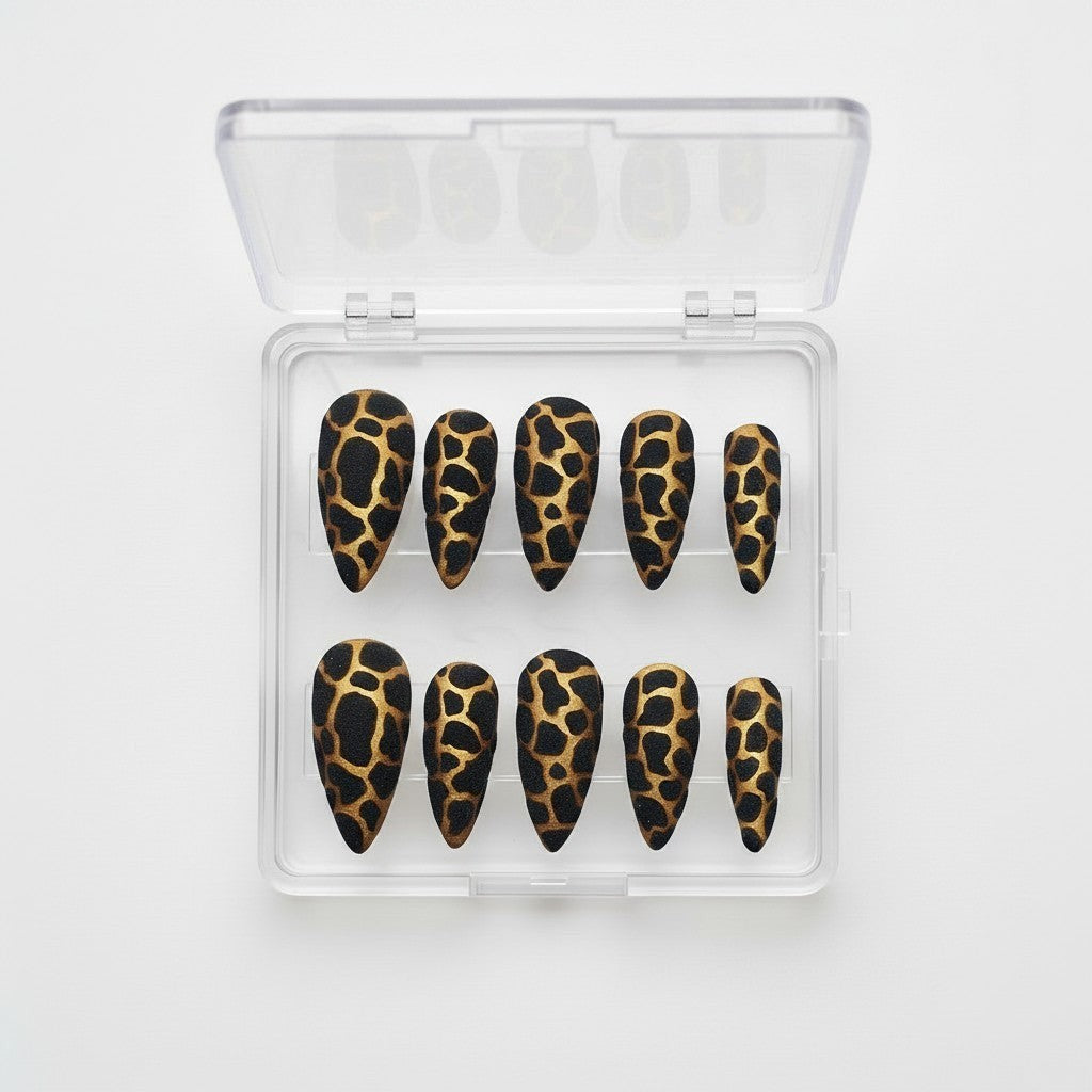 Auntie Cookies Nails stiletto press on nails with black and gold giraffe print and glitter finish.
