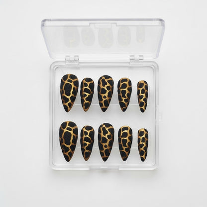 Auntie Cookies Nails stiletto press on nails with black and gold giraffe print and glitter finish.