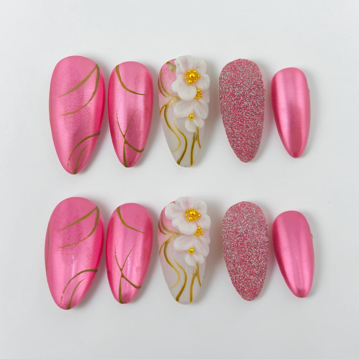 Auntie Cookies Nails pink chrome almond press-on nails with gold lines and 3D floral accent.
